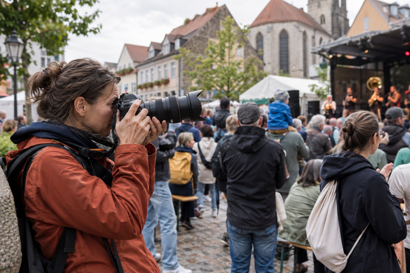 Bildberichterstatterin fotografiert eine öffentliche Veranstaltung aus der Menge heraus Bildberichterstatterin fotografiert eine öffentliche Veranstaltung aus der Menge heraus